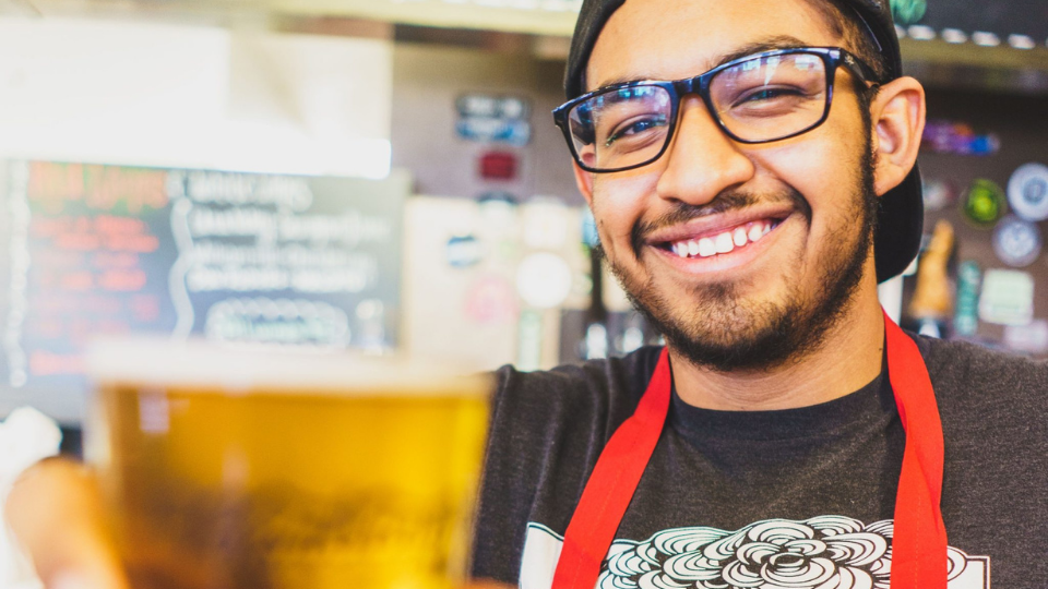 Smiling man serving a craft beer