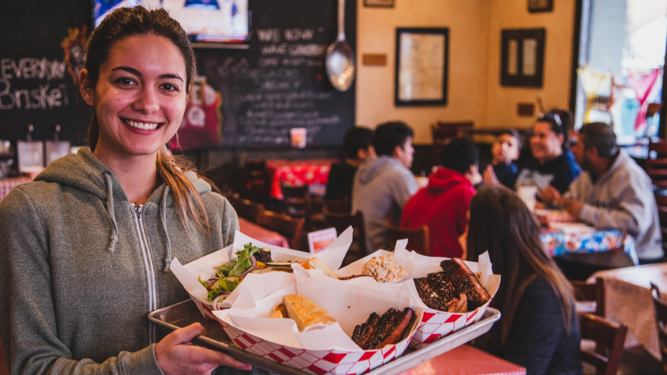 Smiling girl holding plate of pork ribs and salad